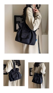 Detailed view of black canvas drawstring tote bag with front pocket and side blue label
