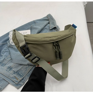 Détail du sac croissant en nylon vert olive montrant la texture et les tirettes tressées
