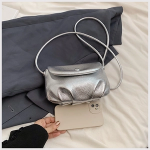 Silver metallic dumpling bag with pebble texture compared to a smartphone for size