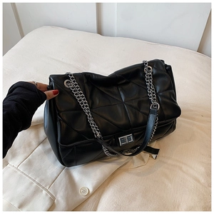 Detailed close-up of quilted black shoulder bag with silver chain strap and metal clasp