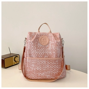 Détail du sac à dos à damier rose avec logo ours et texture du tissu tissé