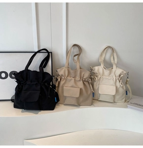 Three pleated tote bags in black, khaki, and cream with drawstring closure and front pocket