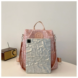 Détail du sac à dos en toile à damier rose avec patch logo et capacité de rangement