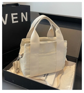 Detail of beige canvas tote bag with adjustable strap inside a luxury gift box packaging