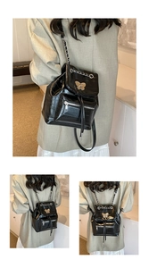 Detail of black faux leather backpack with golden butterfly clasp and chain straps