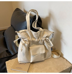 Detail of drawstring tote bag featuring front flap pocket and adjustable shoulder strap
