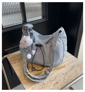 Detail of light blue pleated half-moon bag with satin finish and white cloud charm