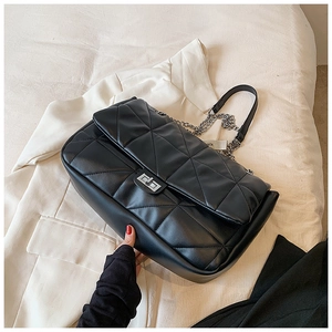 Detail of black quilted leather shoulder bag with silver twist lock and chain strap