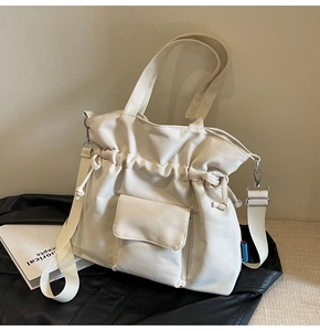 Close-up of cream canvas tote bag with drawstring, side tag and adjustable strap details