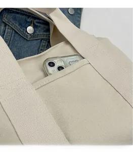 Detail of cream canvas tote bag showing outer pocket with smartphone storage space