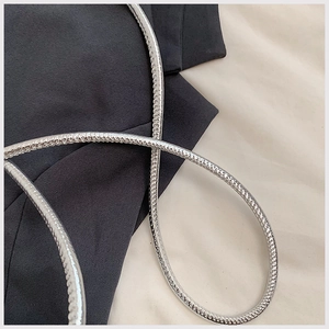Macro shot of silver metal snake chain strap with polished texture on suit fabric
