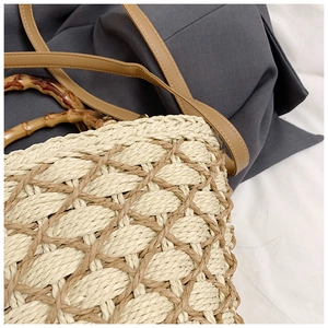 Detailed view of woven straw texture with bamboo handle and leather shoulder strap