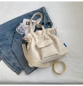 Close-up of cream canvas tote bag with drawstring closure and front flap pocket