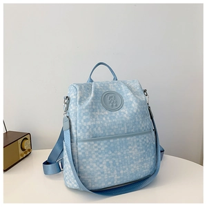 Détail d'un sac à dos bleu clair à texture tissée avec emblème d'ours et poignée