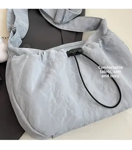 Detail of light blue shoulder bag with pleated texture and adjustable metal strap buckle