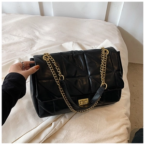 Detail of black quilted leather shoulder bag featuring gold chain and square twist lock