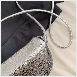 Macro shot of silver metallic textured crossbody bag with detailed pebble grain and chain