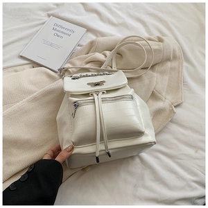 Close-up of beige crocodile pattern backpack with butterfly clasp and chain detail