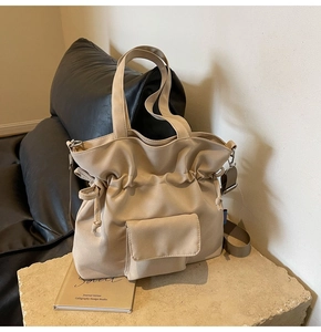 Detail of beige drawstring tote bag with front flap pocket and adjustable strap
