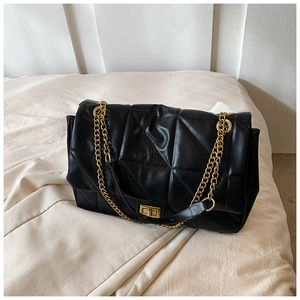 Detail of black quilted shoulder bag featuring golden chain strap and metal swivel lock
