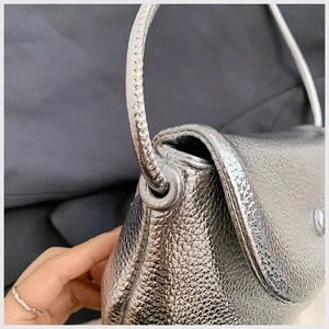 Detail shot of silver metallic grain leather bag with ring handle and fine stitching