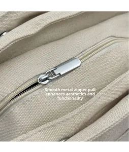 Detailed close-up of smooth silver metal zipper head on beige canvas tote bag