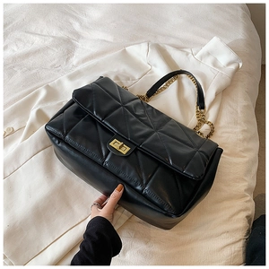 Close-up of black quilted shoulder bag with gold chain strap and turn-lock closure