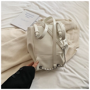 Detail of white crocodile texture backpack with silver chain decor and metal buckles