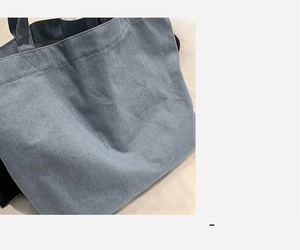 Close-up of light blue denim tote fabric with reinforced stitching and soft texture