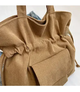 Detail of soft brown corduroy tote bag showing vertical texture and front flap pocket