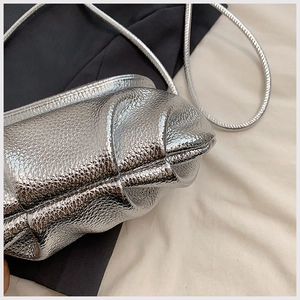 Detailed view of silver metallic pleated cloud bag with grainy texture and chain strap