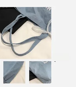 Detail of light blue denim tote bag featuring lace bow and white 'More' embroidery