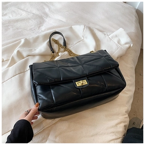 Detail of black quilted leather shoulder bag featuring gold chain and turn-lock closure