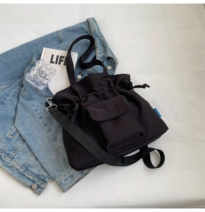 Detail of black canvas drawstring tote bag with front pocket and thick nylon shoulder strap