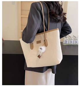 Detail of cream tote bag with cartoon embossing and contrast brown shoulder strap