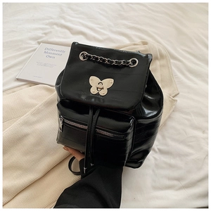 Detail of black glossy mini backpack with metal butterfly clasp and chain trim