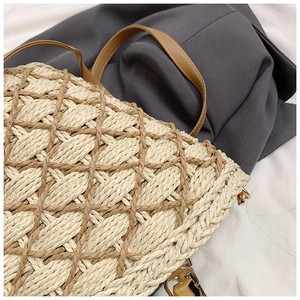 Detailed view of woven straw texture with brown leather strap and gold metal buckles