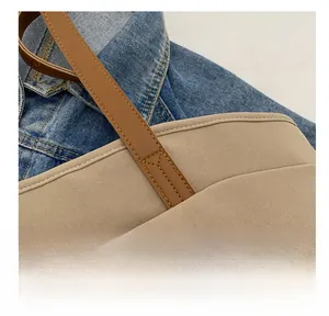 Detail showing the reinforced brown handle stitching on a khaki canvas tote bag