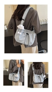 Detail of light blue pleated shoulder bag with white cloud plush charm and drawstring