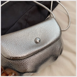 Close-up of metallic silver cloud bag showing detailed litchi texture and metal buckle