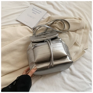 Detail of silver metallic backpack featuring chain straps and a front zipper pocket