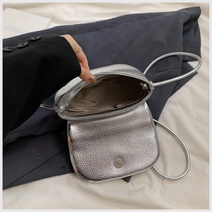 Detail of silver metallic cloud bag featuring magnetic closure and inner zipper pocket