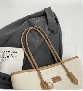 Detail of cream floral embossed tote bag with brown handles and leather brand label
