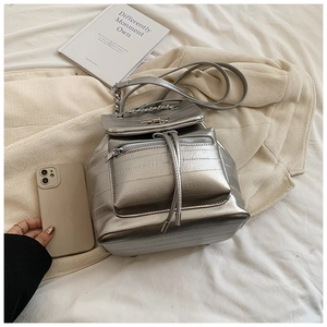 Macro detail of silver metallic backpack featuring quilted seams and chain strap accents