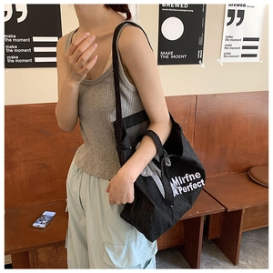 Detail of black denim tote bag with white Mirfne Perfect text and mesh bow decoration