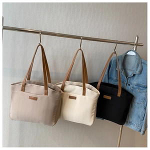 Three canvas tote bags in khaki, beige, and black with brown leather handles