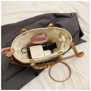 Top view of woven straw tote bag interior with bamboo handle and adjustable leather strap