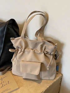 Minimalist beige canvas pleated tote bag with drawstring closure and front pocket