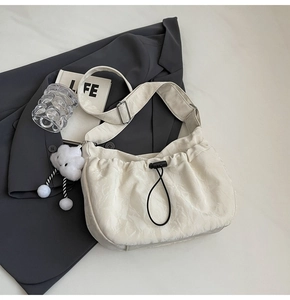 Detail of off-white pleated shoulder bag with black drawstring and plush cloud charm