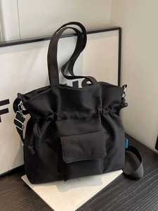 Minimalist black canvas pleated tote bag with drawstring closure and adjustable straps